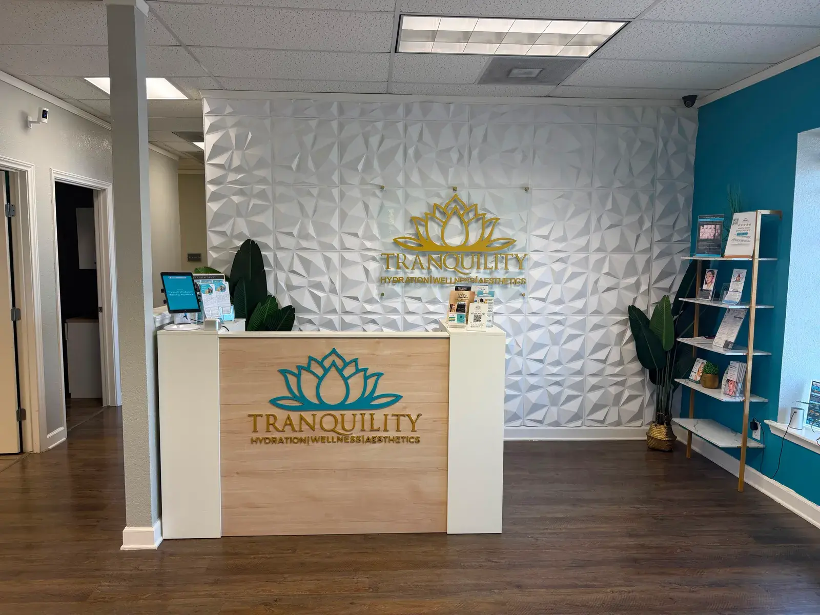 The Tranquility front desk in Mansfield, with a gold lotus sign mounted on a white sculpted wall behind it