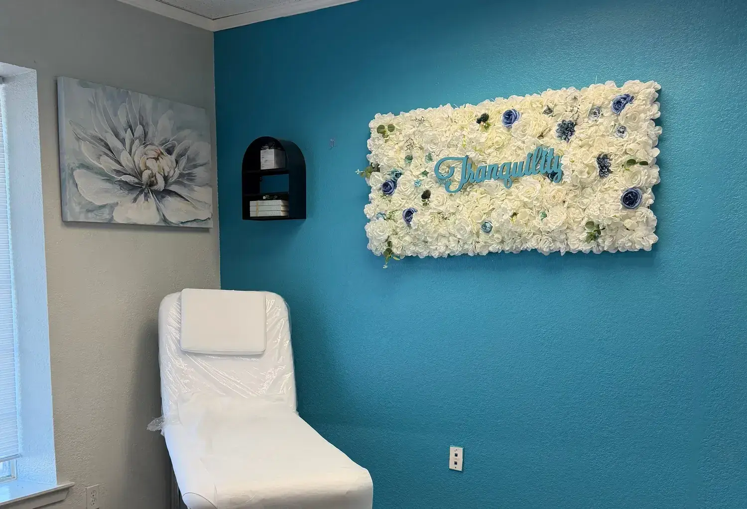 A private treatment room at Tranquility, with a white floral wall spelling Tranquility above the treatment couch