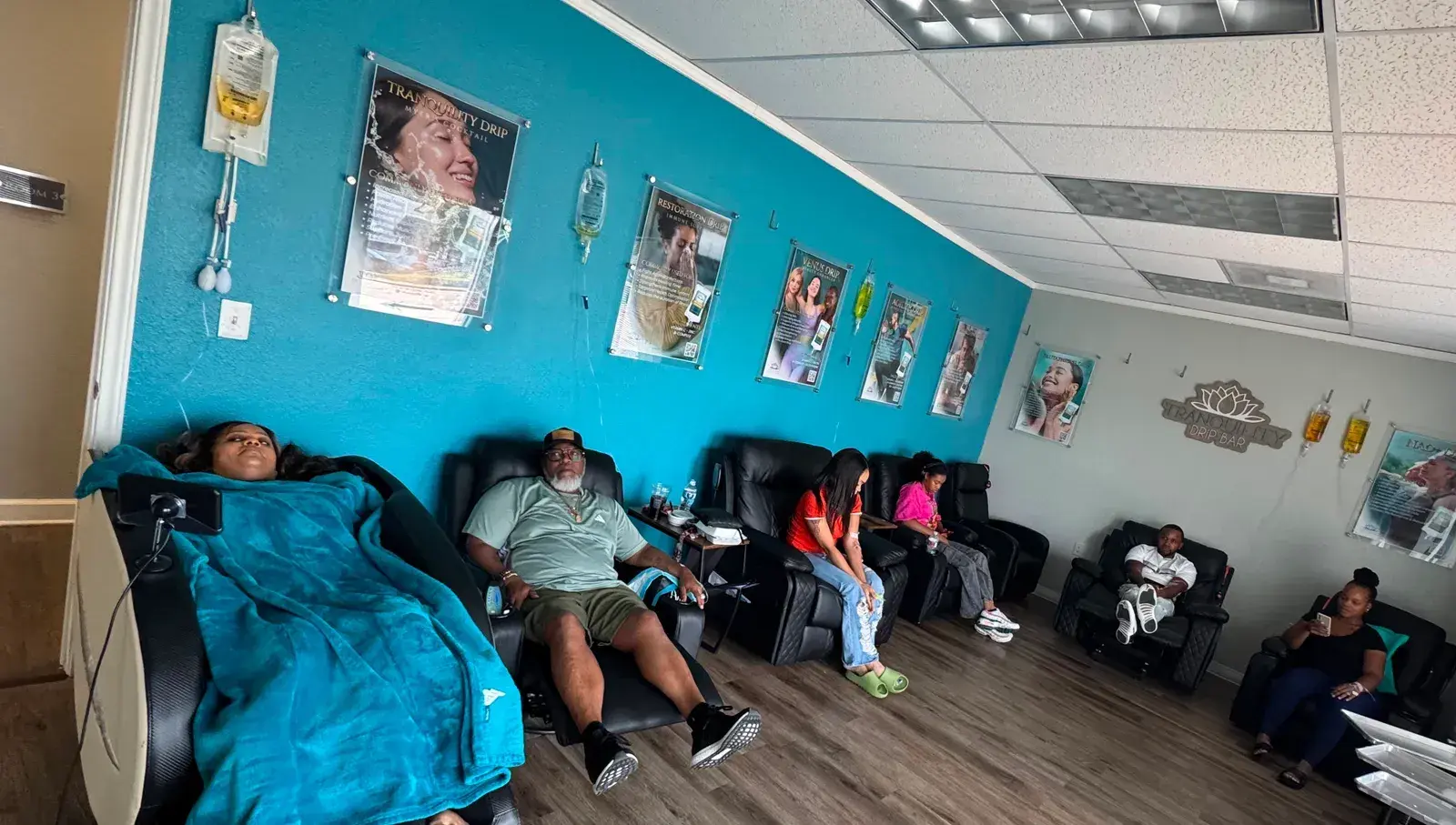The Tranquility drip bar in Mansfield, with guests resting in reclining chairs along a teal wall of drip menus